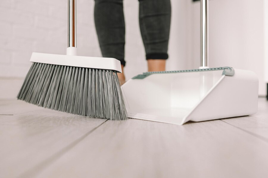 Preserving Elegance: The Benefits of Regular Stripping and Waxing - young-woman-with-broom-dustpan-cleaning-home